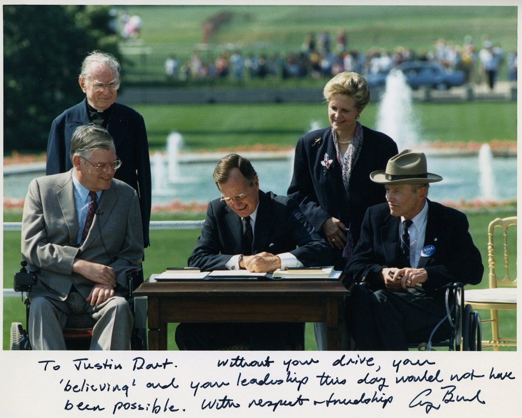 Photo_of_President_George_H._W._Bush_signing_the_Americans_with_Disabilities_Act_inscribed_to_Justin_Dart,_Jr.,_1990